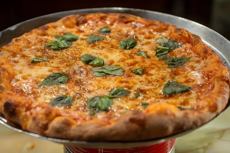 A Margherita pizza with basil leaves on a raised tray
