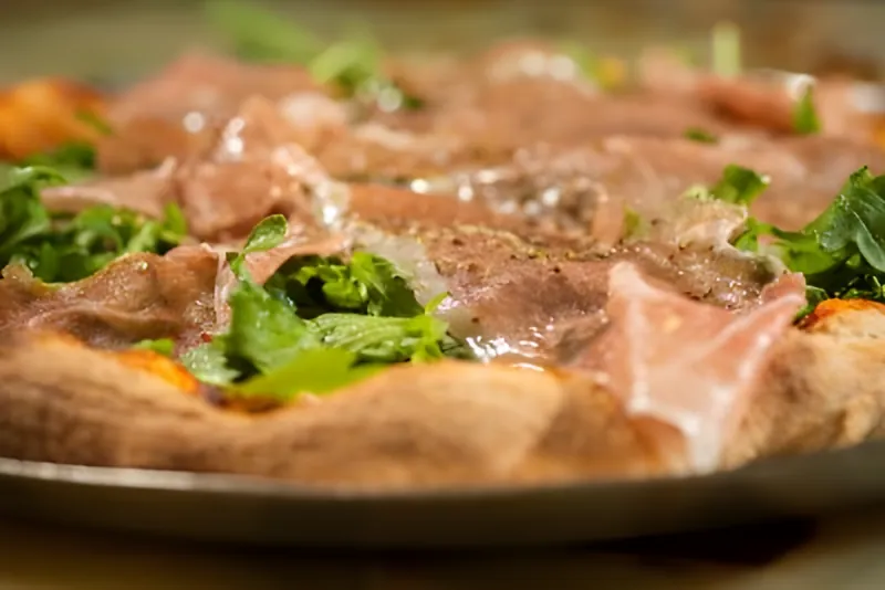 Pizza topped with prosciutto di Parma and arugula