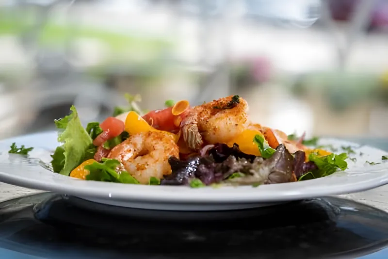 Sautéed shrimp over mixed greens with oranges and tomatoes